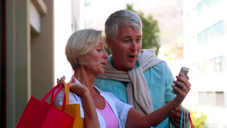 pareja feliz en el día de compras mirando el teléfono inteligente