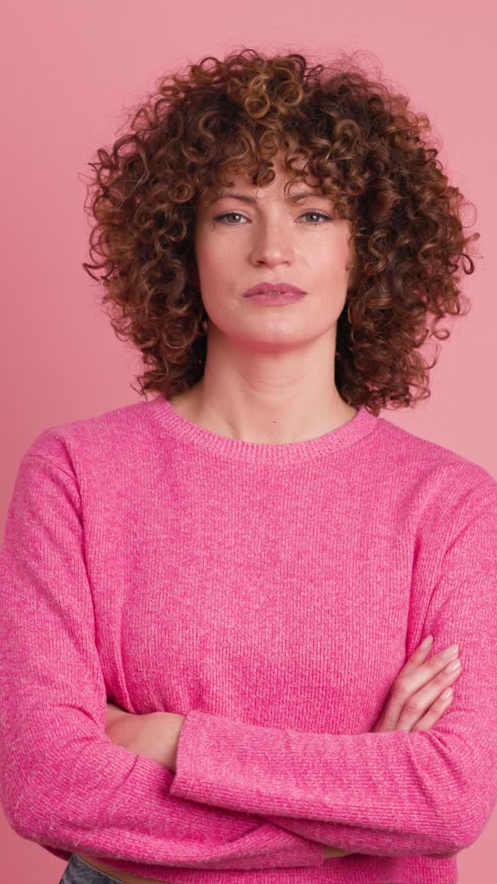 Giovane donna in disaccordo che scuote la testa con la bocca contorta su sfondo rosa. Filmato verticale