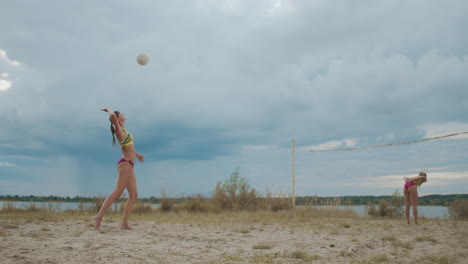 Pase-De-Servicio-Y-Ataque-En-Un-Partido-De-Voleibol-De-Playa-Entre-Dos-Equipos-Femeninos-En-Un-Día-Nublado-De-Verano-En-Cámara-Lenta