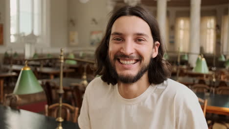 young male student laughing at camera in library