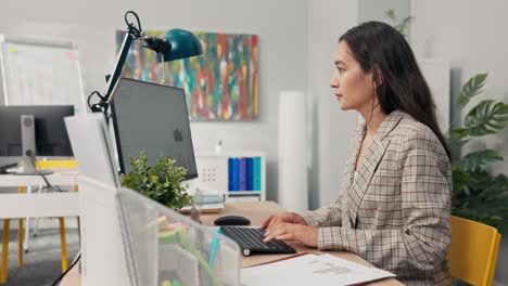 un atractivo y experimentado contador de la compañía se sienta en la oficina frente a una computadora comprobando datos estadísticos tablas de salarios de empleados comparando diagramas de papel con los electrónicos analista financiero