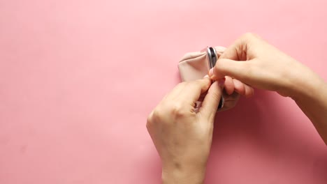 manos abriendo y cerrando un bolso rosa claro