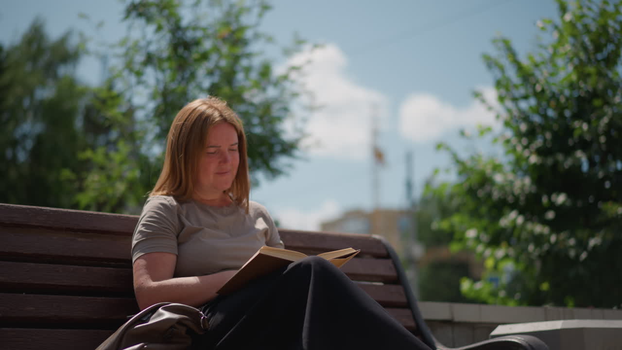 Vrouw die buiten leest en een bladzijde omslaat van een open boek onder zacht, natuurlijk licht, kalme en vredige sfeer vastgelegd in subtiele bewegingen met warme tinten en een vloeiende schakering