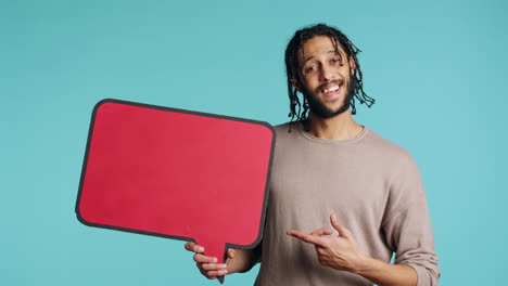 happy man holding red speech bubble sign, studio background