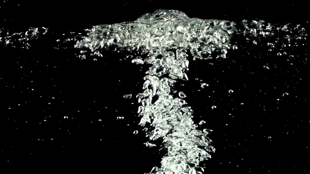 Bolle d'aria trasparenti che salgono nell'acqua su sfondo nero