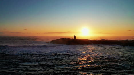 Passing-the-lighthouse-under-the-beautiful-sunset-over-the-ocean-in-South-Iceland---aerial