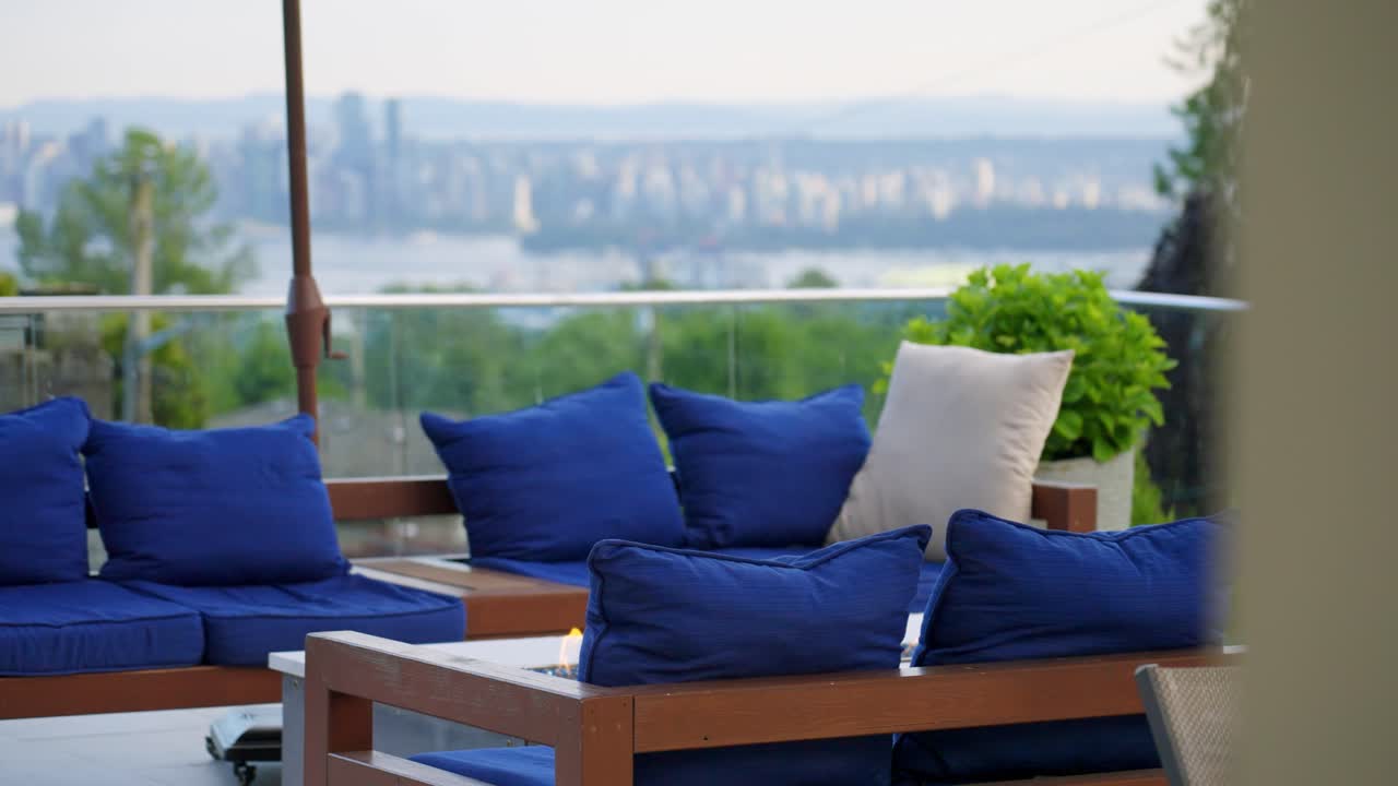 Elegante patio esterno con sedute imbottite blu con vista sullo skyline e sull'acqua della città di Vancouver, che mette in mostra la vita urbana moderna, il relax e il lifestyle di lusso