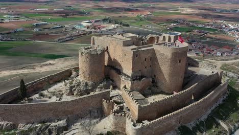 vuelo orbital sobre una fortaleza amurallada reconstruida de la edad media y con acceso a visitas con personas ubicadas en una colina con buenas vistas y un fondo de población en un día de primavera toledo españa