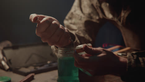 a bombmaker assembles a bomb in his workshop at night