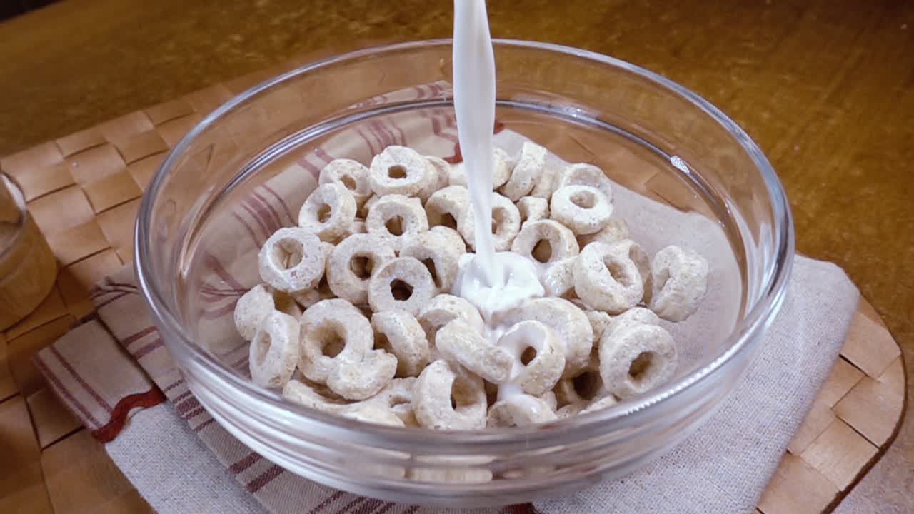 copos de avena crujientes en un tazón para un delicioso desayuno matutino con leche. cámara lenta con toma de seguimiento de rotación.