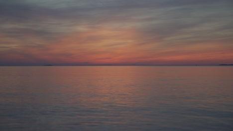 the sun is setting at the croatian seaside in summer above gentle waves