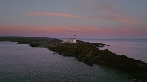 Luftdrohne-Fliegt-über-Der-Leuchtturmlandschaft-Der-Halbinsel-Menorca-Bei-Sonnenuntergang,-Rosa-Skyline,-Goldene-Stunde,-Spanisches-Wahrzeichen