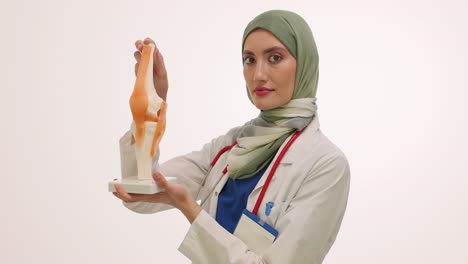 female doctor in hijab holding a knee joint anatomy model