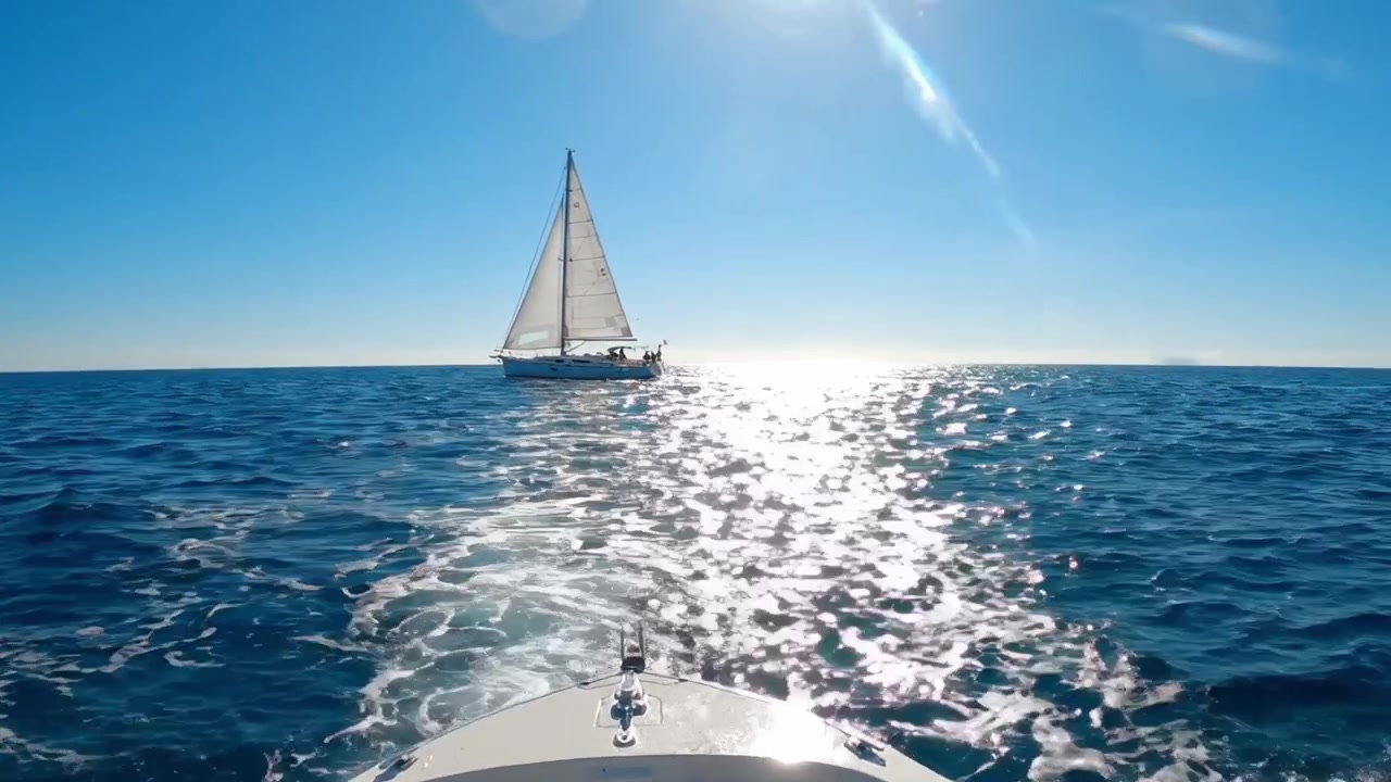 A Serene Journey on the Open Waters: Captivating Views of a Sailing Boat Gliding Through Sparkling Ocean Waves Under a Clear Blue Sky