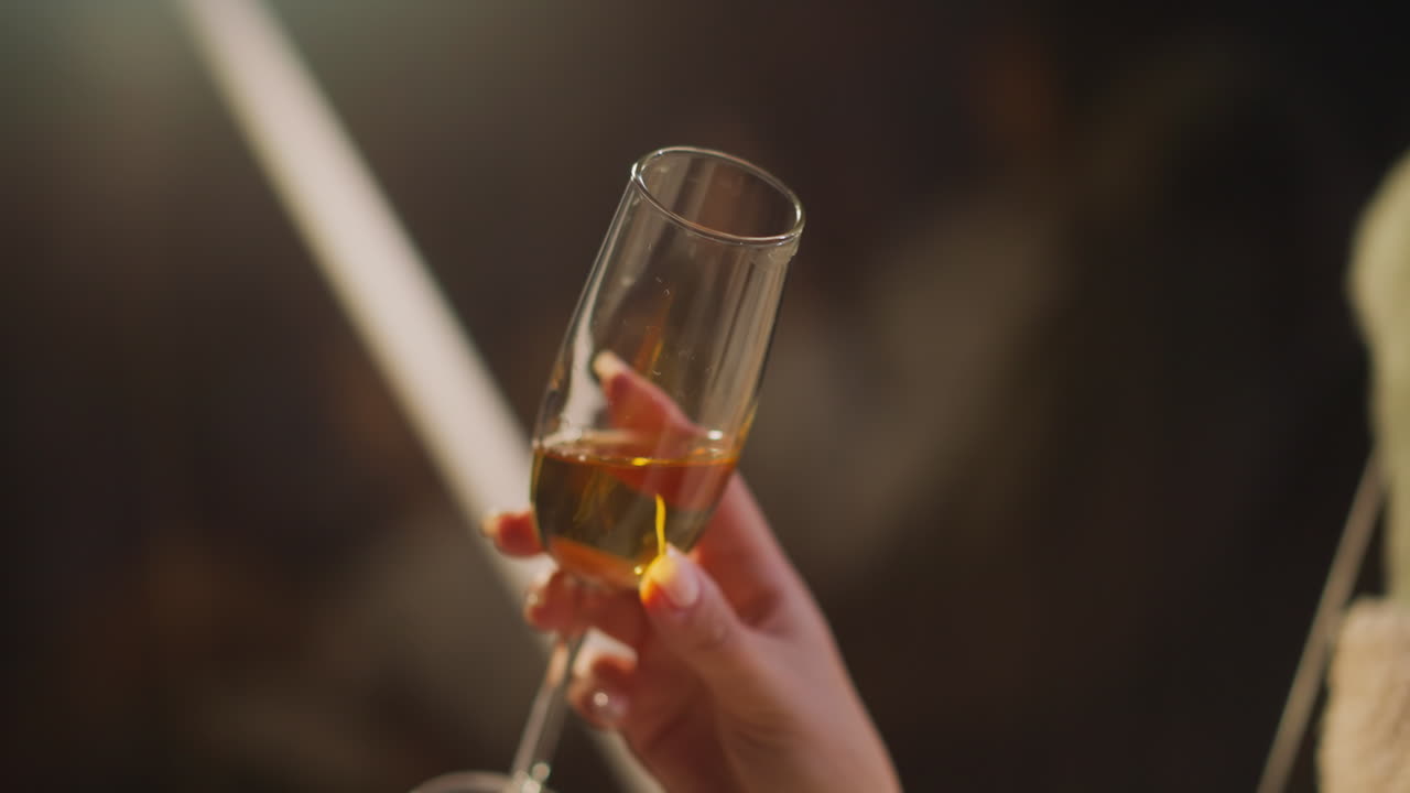 여성 손은 알코올 음료의 와인 글래스를 회전시키며 밤 생활을 내려다보는 희미하게 조명된 호텔 방에서 술을 마시는 즐거움을 즐기고 있습니다. 건강과 여성 알코올 중독에 대한 알코올의 해.