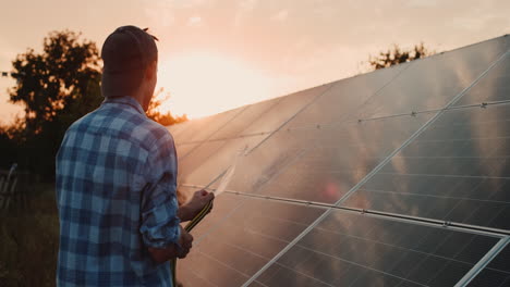 joven lava paneles solares con una manguera 1