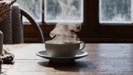 steaming hot drink on a wooden table by a window