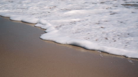 primer plano de mano de las olas rompiendo en una playa vacía