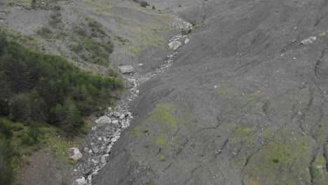 Drone-video-flying-over-a-deep-gorge-canyon-river-flying-up-mountain-tilting-up