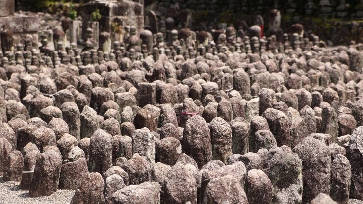 Forvitrede stenbuddhistiske mindefigurer ved Adashino Nenbutsu-ji-templet, der danner et særpræget helligt landskab i Kyotos historiske Arashiyama-distrikt.