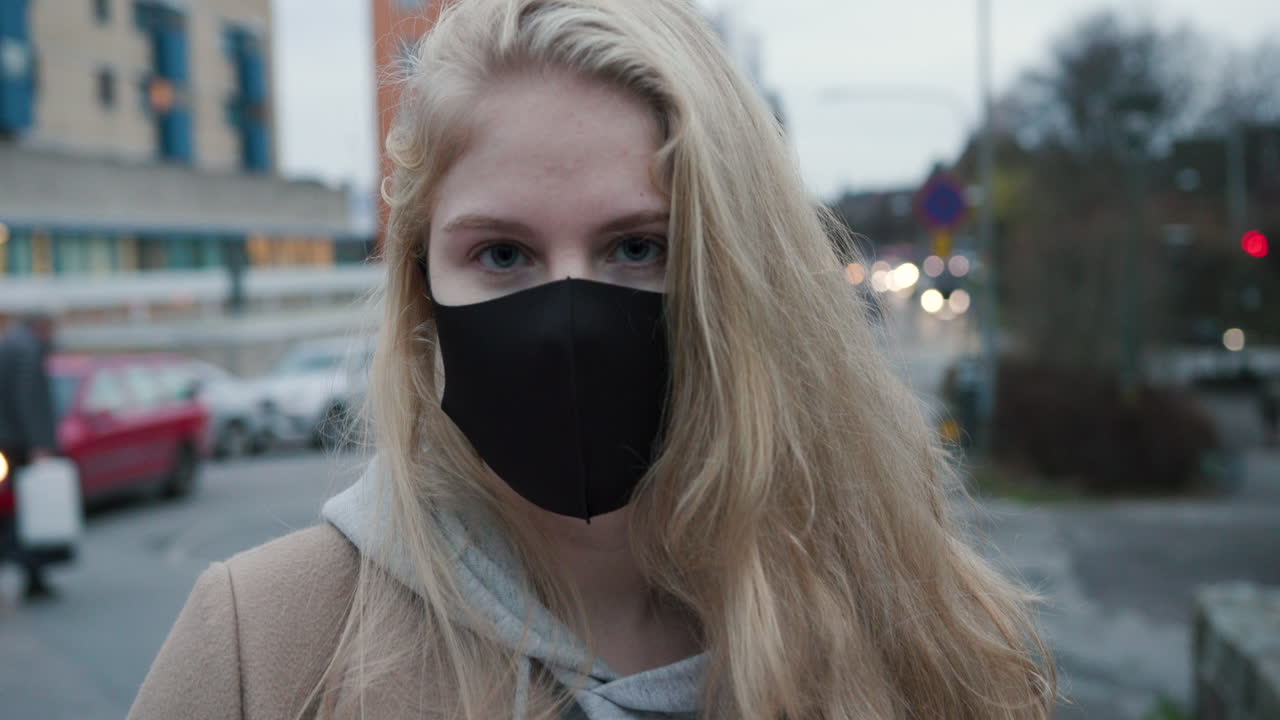 Blonde woman with black face mask holding a package, zoom in, slow motion