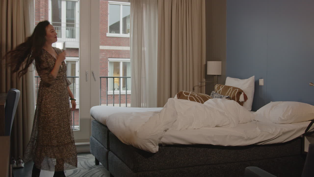 Wide view of an attractive Chinese woman making selfies while in a hotel bedroom
