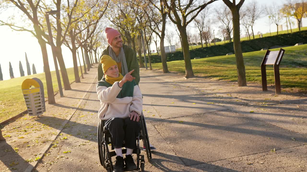 Man pushing woman in wheelchair in a park during autumn