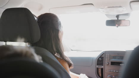 mother talking to children in back seat of car as family drive on family vacation