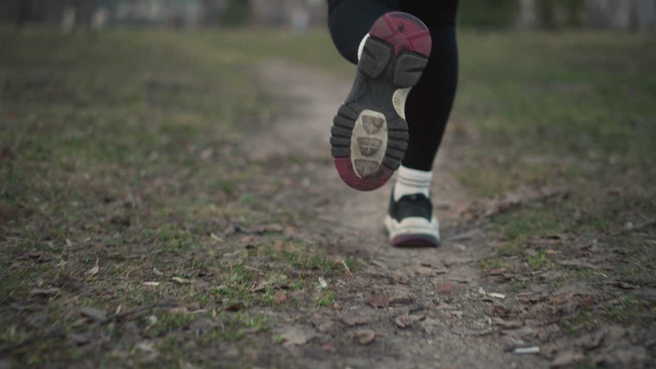 Female Jogs Forward, Young Woman Runs Through Woods, Girl In Red Hoodie Moves Swiftly, Woman In Forest Trail With Rhythmic Steps, Energetic Female Runner On Narrow Woodland Path Wearing Red Hoodie