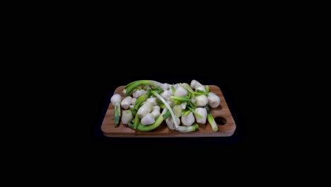 peeled and chopped onions on a wooden cutting board isolated in black background. - pushout shot