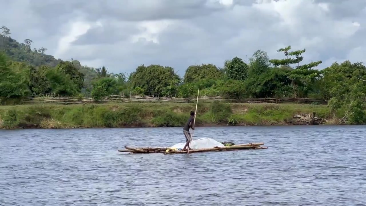 En mand krydser Antainambalana-floden på en tømmerflåde. Madagaskar