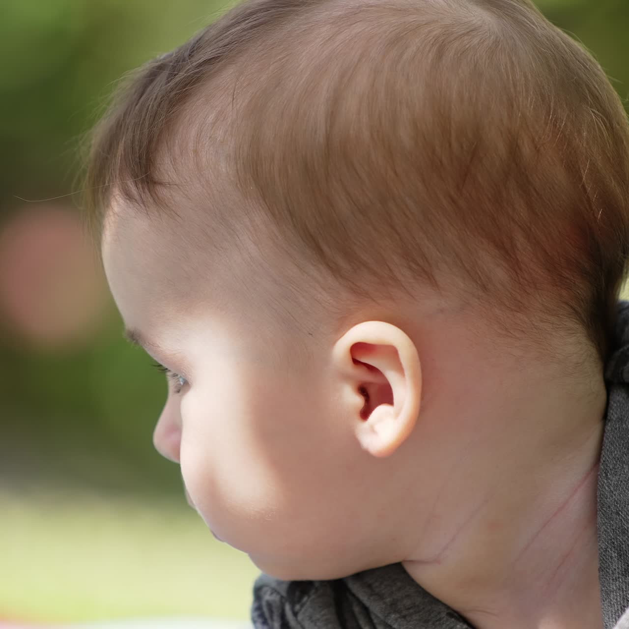 Adorabile neonato caucasico all'aperto nella natura. Il bambino guarda di lato e poi guarda seriamente nella fotocamera. Primo piano
