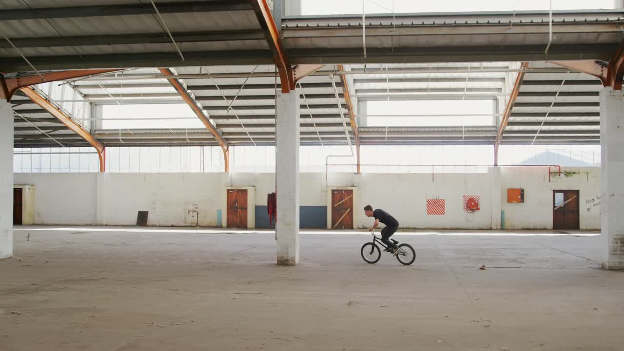 Ciclista BMX in un magazzino vuoto.