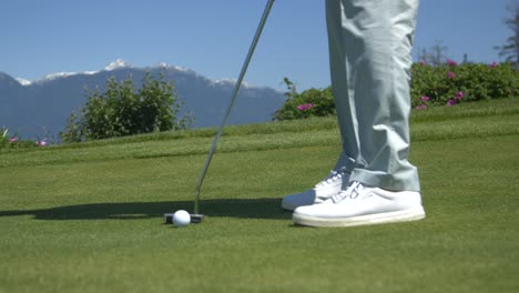 golfer putting on the green with mountains in background