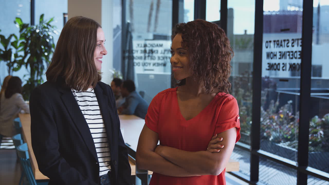 Portrait Of Two Businesswomen Standing In Modern Open Plan Office Together