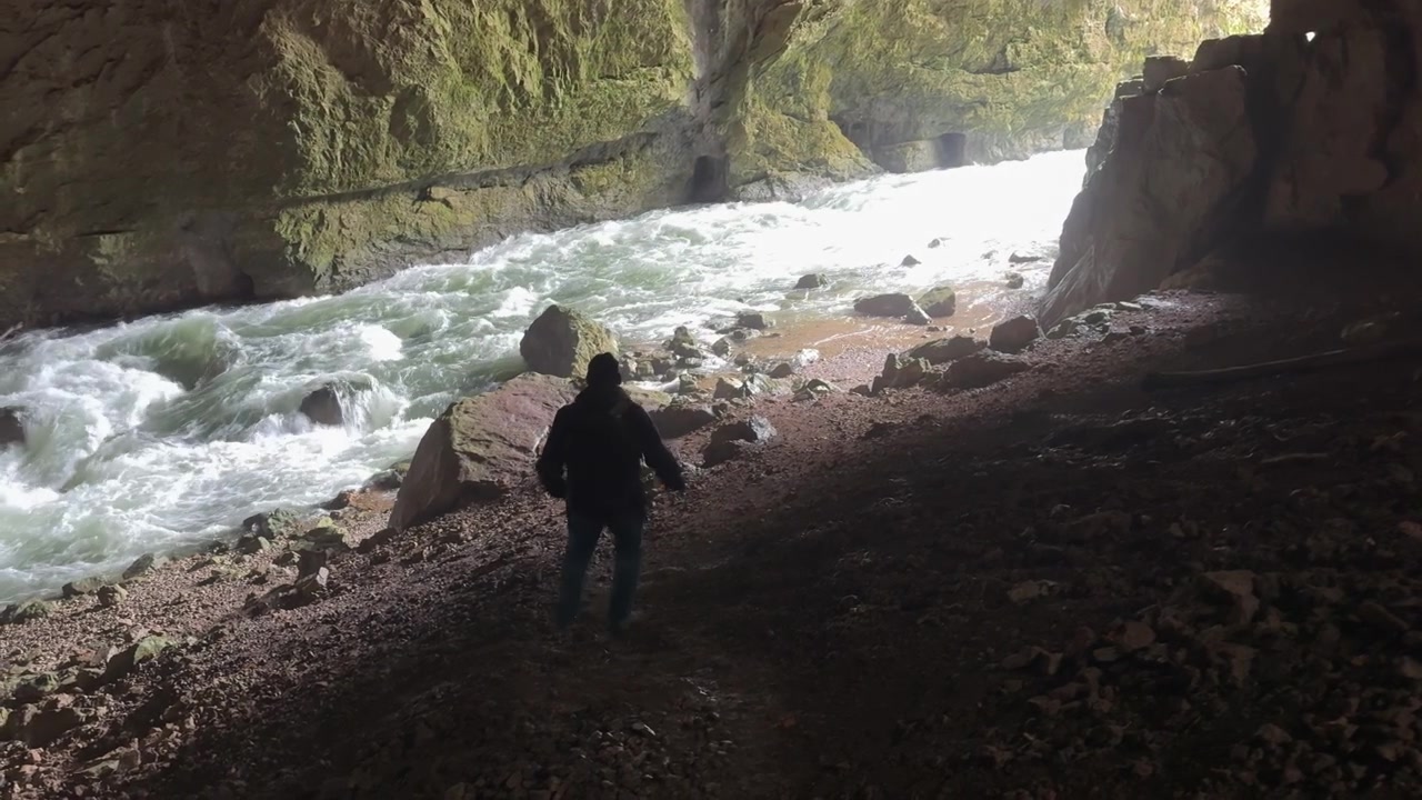 Adventurous explorer walking inside Weaver Cave, or Tkalca jama, in Slovenia next to an underground river canyon