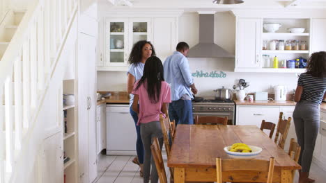 Family-With-Teenage-Children-Laying-Table-For-Meal-In-Kitchen