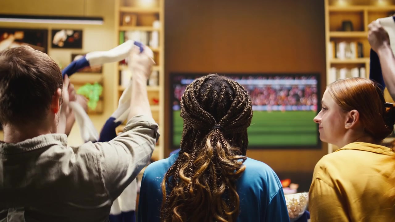 Close-up penggemar sepak bola menonton siaran langsung pertandingan di TV dan makan popcorn