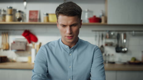 Man-browsing-social-networks-at-laptop-sitting-in-kitchen.-Freelancer-working.