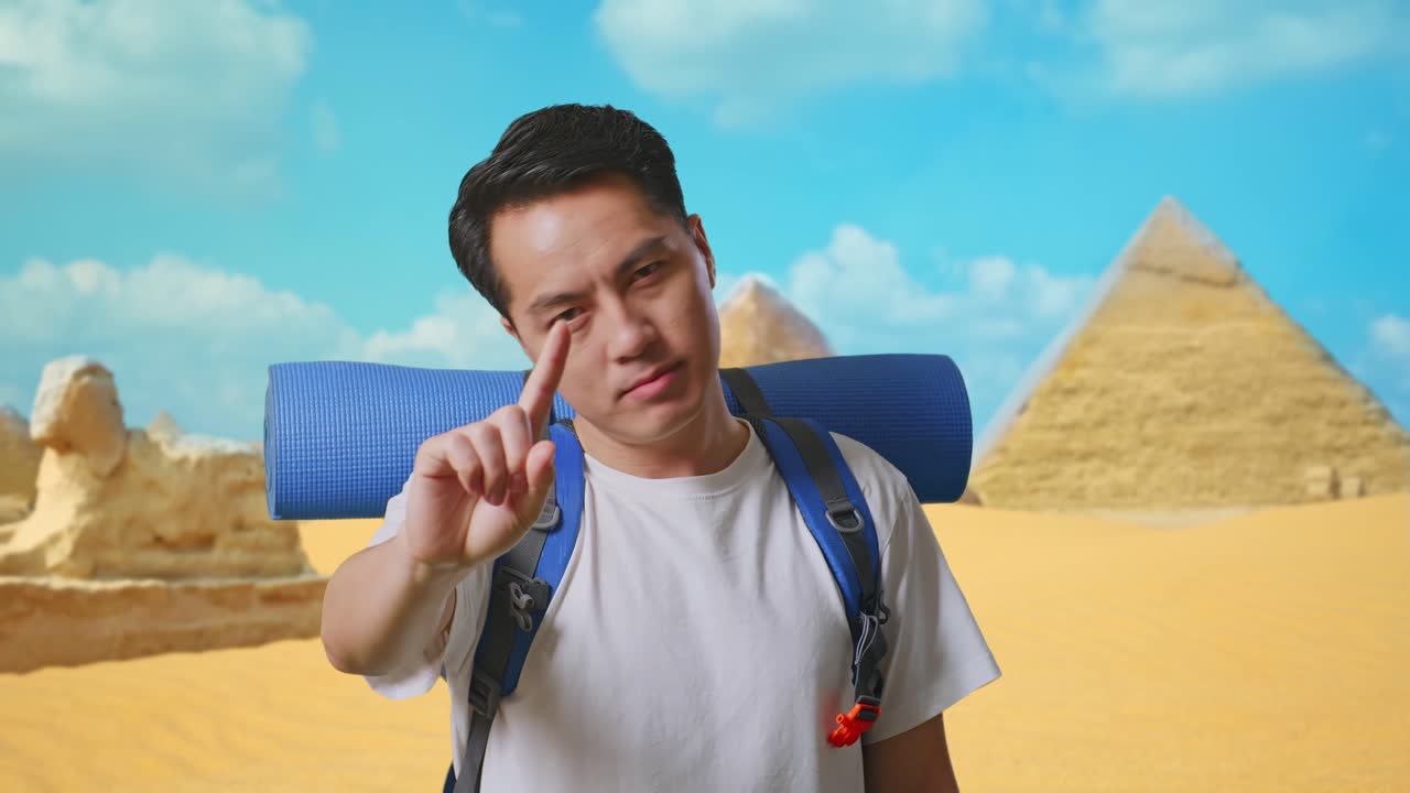 Close Up Of Asian Male Hiker With Mountaineering Backpack Showing No Gesture With Index Finger While Traveling In Pyramid Of Giza