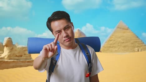 close up of asian male hiker with mountaineering backpack showing no gesture with index finger while traveling in pyramid of giza