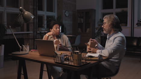 colleagues eating late-night takeout while working in an office