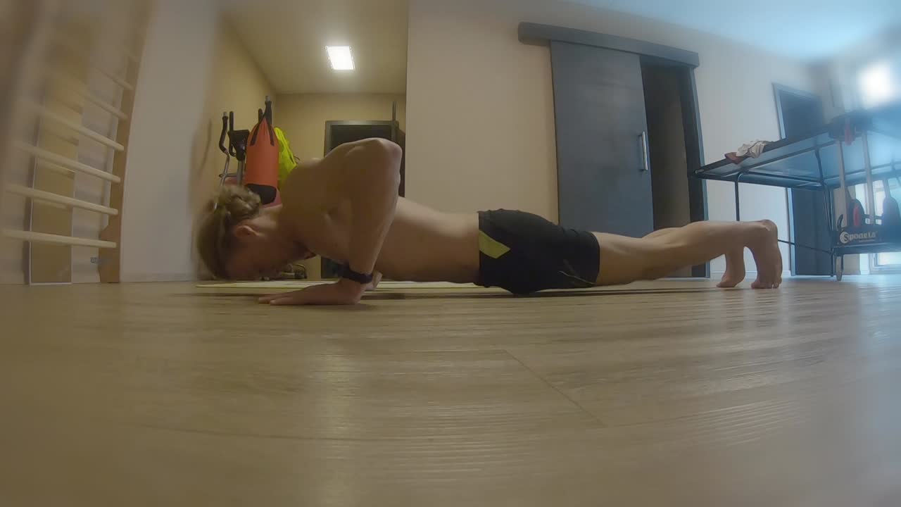 entrenamiento de gimnasio en casa adolescente haciendo flexiones en pantalones cortos sin camiseta fitness