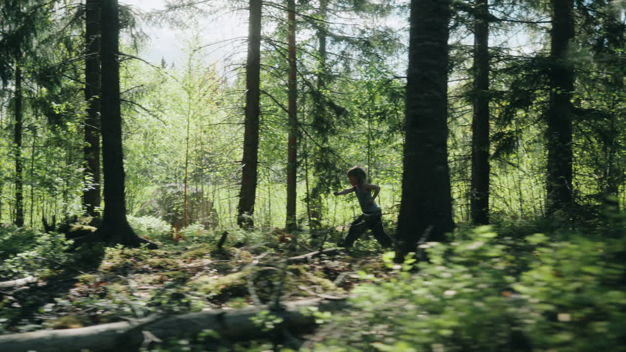 Tracking shot, child runs through woods with sun rays filters through trees