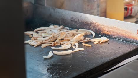 A-close-up-4k-shot-of-caramalized-onions-being-cooked-on-a-hot-flat-stove-top