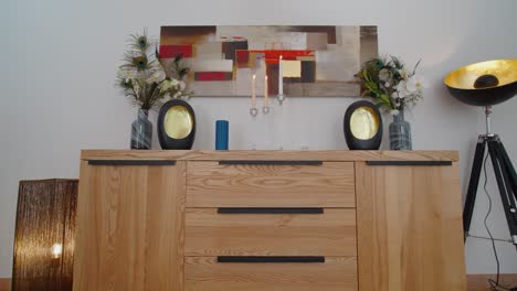 slow pull-out shot of a wooden cabinet with candles and artwork hanging on the wall