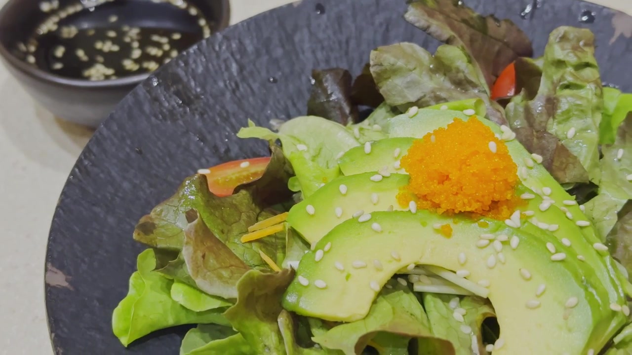 Nærbillede af en frisk avocadosalat i japansk stil, smukt anrettet med blandede grøntsager og traditionel japansk dressing. Sund og farverig salatpræsentation, der viser autentisk japansk madkultur.