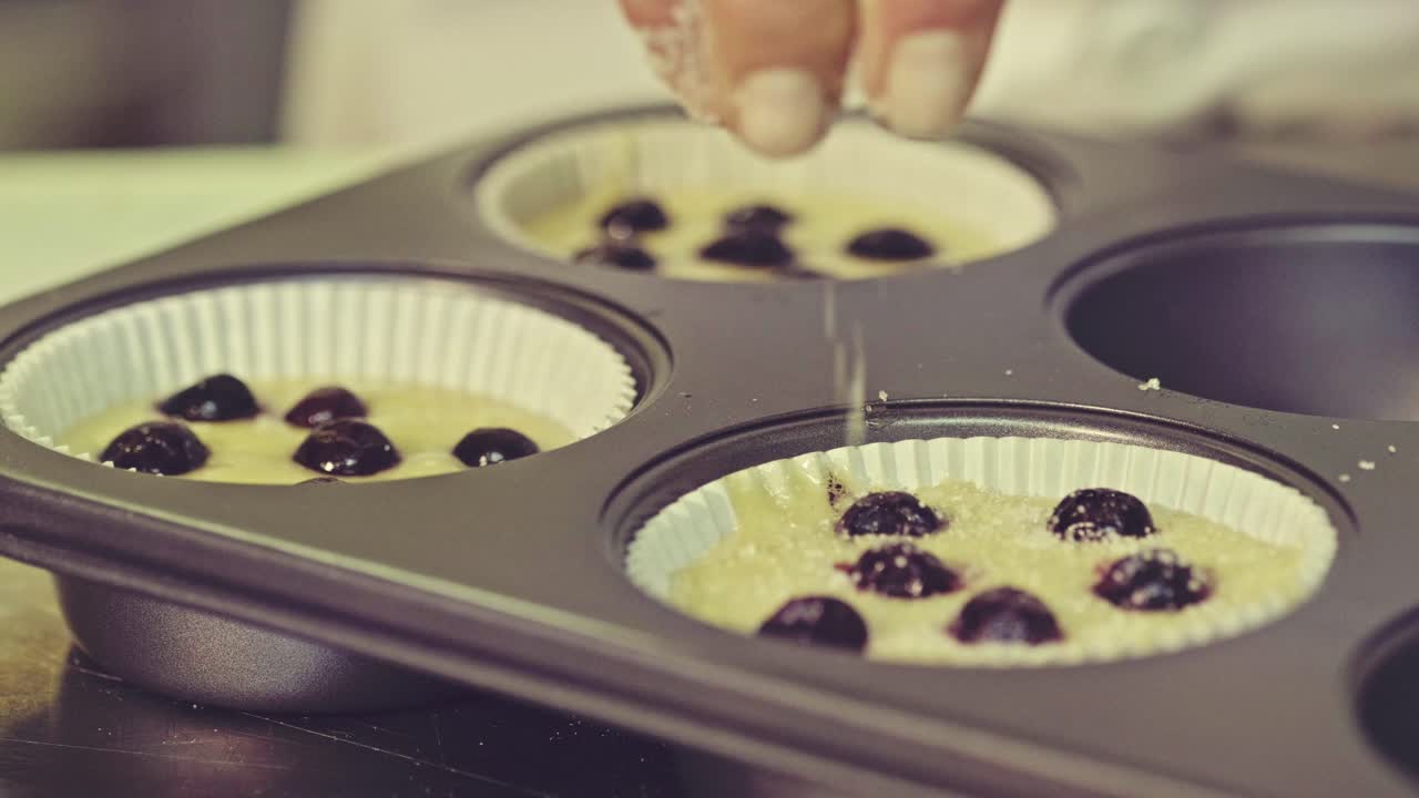 셰프 가 마핀 반죽 에 설탕 가루 를 첨가 하고 있다