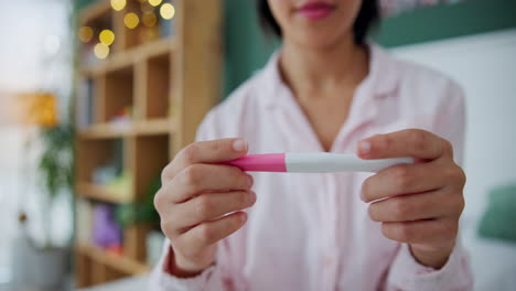 woman holding a positive pregnancy test in bedroom