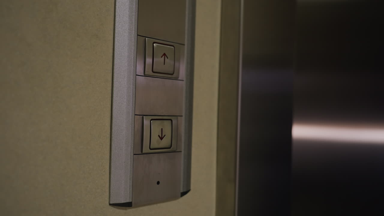 Close-up of hand pressing elevator button, modern metallic elevator panel, upward direction symbol, professional environment, business building, corporate setting, modern design